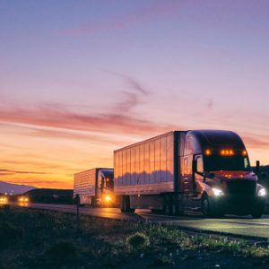 Large semi truck hauling freight on the open highway in the western USA under an evening sky.